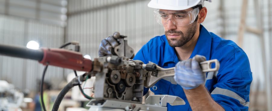 Male engineer using wrench tool repair robot arm welding machine in factory. Technician automation robot in uniform working at robot industrial.